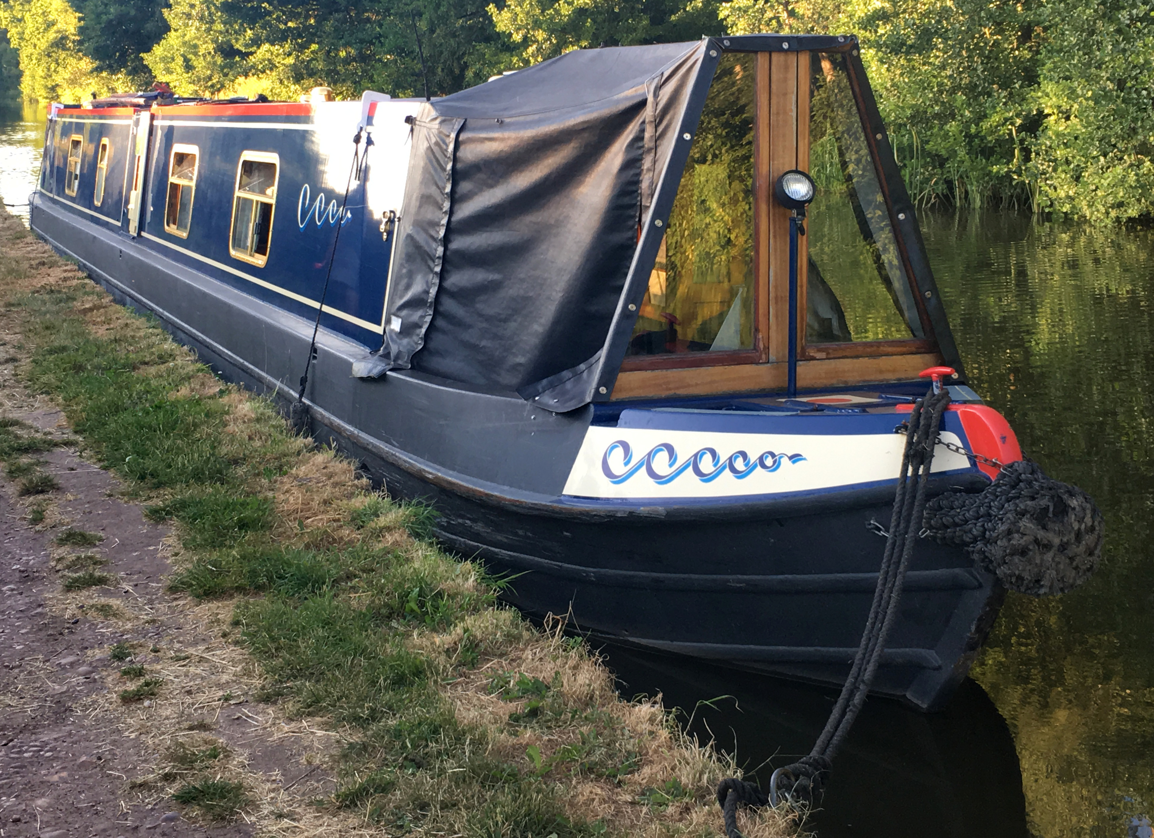 Photograph showing the dark blue canal boat, Vulcan, as viewed fromt the towpath in front of the boat